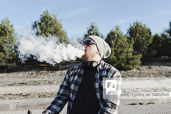 Junger Mann raucht mit einer elektronischen Zigarette