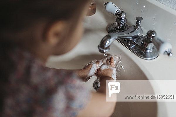 Junges Mädchen im Vorschulalter wäscht sich die Hände im Waschbecken mit Seife