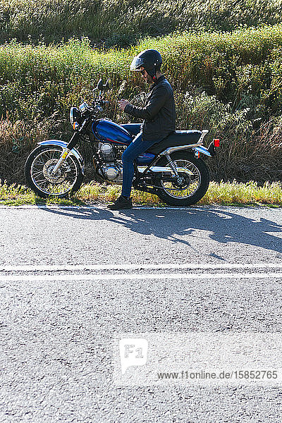 junger Mann  der sich die Route ansieht  der er auf seinem Motorrad mit dem Mo