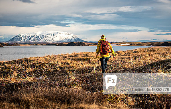 Frau wandert mit Rucksack am See in Island