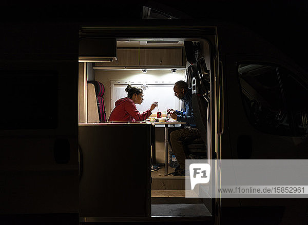 Ehepaar bei einem entspannten Abendessen in einem Wohnmobil während einer Reise.