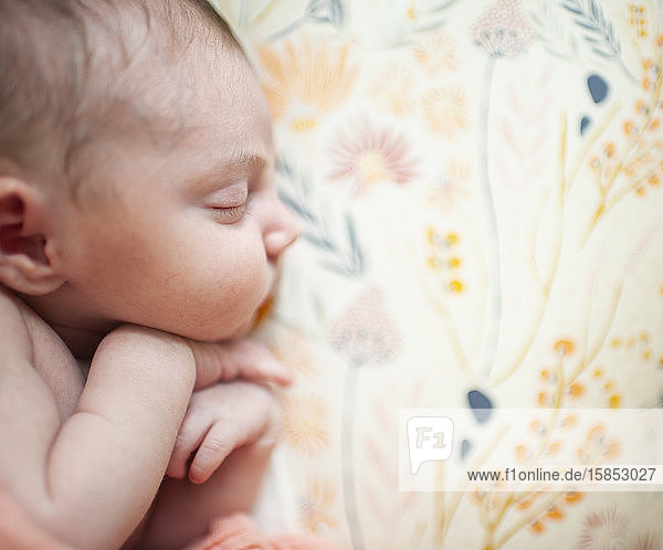 Nahaufnahme des Profils neugeborener Mädchen im Schlaf mit gefalteten Händen