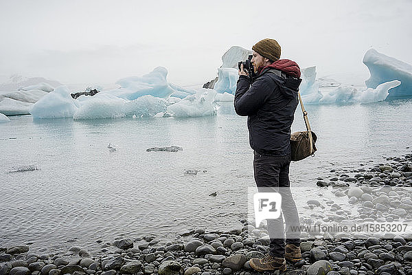 Man taking a photo at Jokulsarlon glacier lagoon at dusk