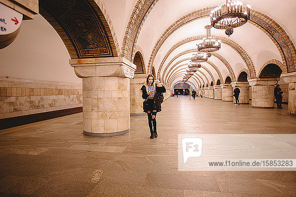 Junge Frau benutzt Smartphone beim Gehen in der U-Bahn-Station