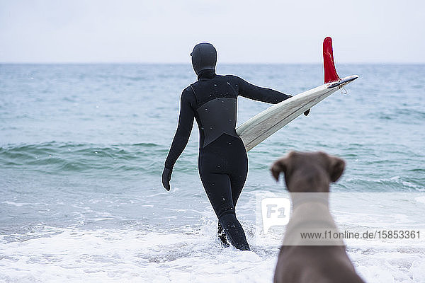 Young woman and her dog going winter surfing in snow
