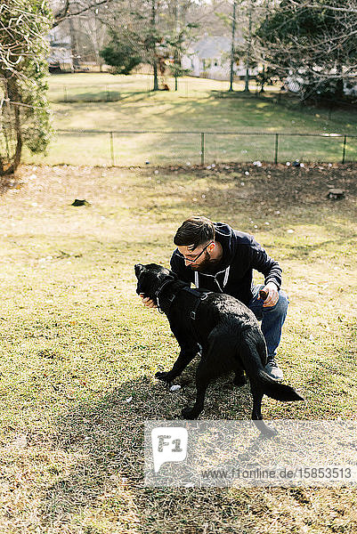 Ein junger Mann spielt mit seinem Hund.