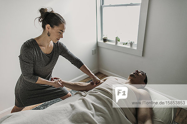 Eine weibliche Massagetherapeutin behandelt den Bizeps eines Mannes