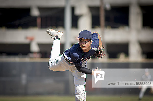 teen baseball player pitcher in blue uniform on the mound
