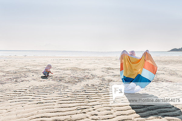 Toddlers at the beach with bright coloured towel