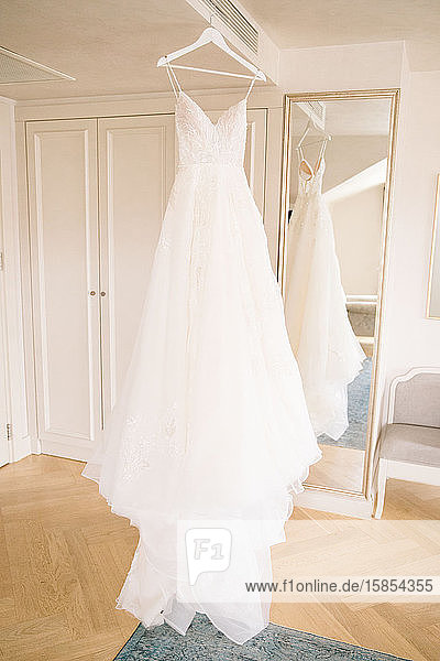 Ein weißes Hochzeitskleid  das auf dem Kleiderbügel aufgehängt ist. Der Kauf eines Hochzeitskleides.