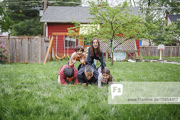 Eine lächelnde Familie stapelt sich beim Spielen im Hinterhof in einer menschlichen Pyramide
