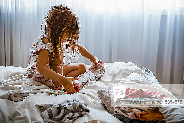 4-jähriges Mädchen faltet Handtücher auf einem Bett