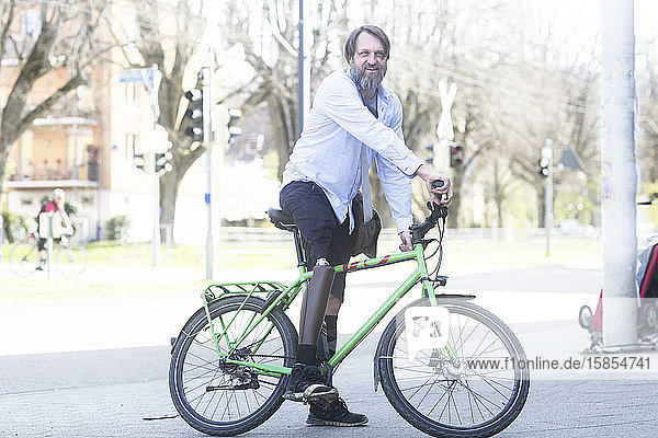 älterer Mann mit Beinprothese  der mit einem Fahrrad nach Hause kommt