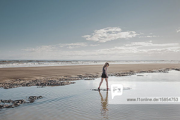 Junges Mädchen geht am Strand durchs Wasser
