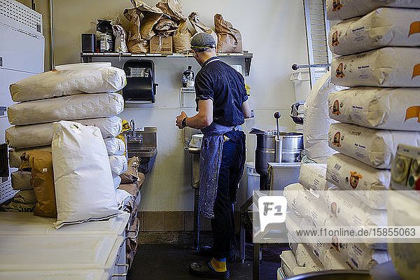 Rückansicht Porträt eines Bäckers umgeben von Mehlsäcken in der Küche