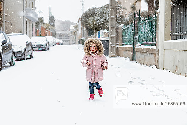 Junges Mädchen spielt auf der Straße im Schnee in Frankreich vor der Kamera