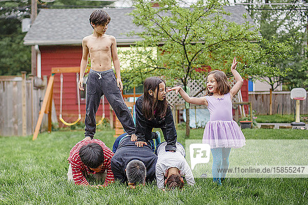 A playful  family builds human pyramid together in backyard