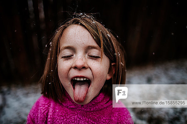 junges Mädchen  das im Winter versucht  Schneeflocken auf der Zunge zu fangen