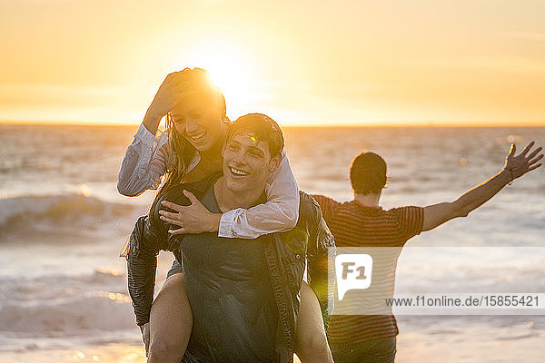 Gruppe von Teenagern  die sich bei Sonnenuntergang am Strand vergnügen