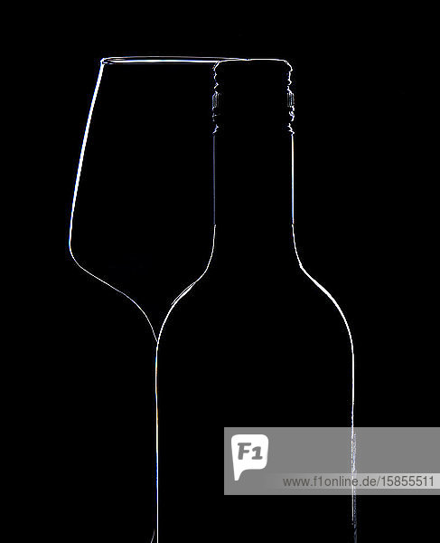 Flasche und Glas Wein auf schwarzer Hintergrundsilhouette