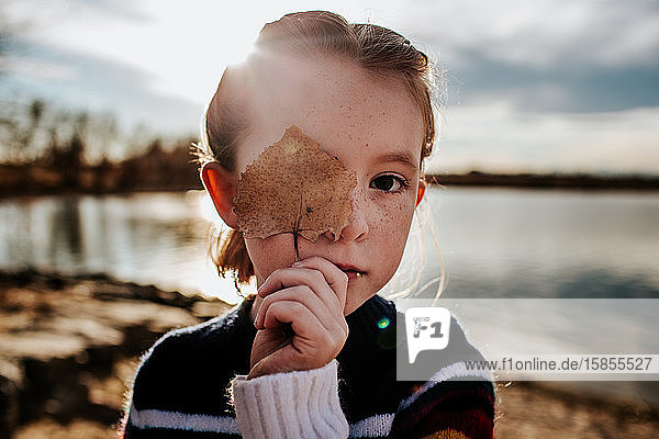 Porträt eines Mädchens mit einem Blatt  das die Hälfte ihres Gesichts bedeckt