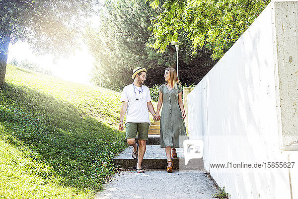 Glückliches junges Paar geht in einem Park spazieren und hält sich an den Händen