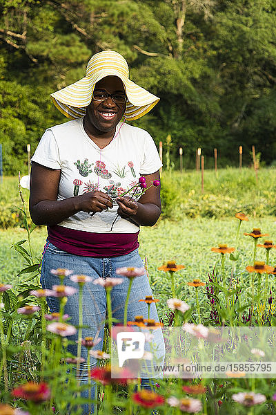 Junge lächelnde Frau schneidet Blumen in einem Blumenfeld