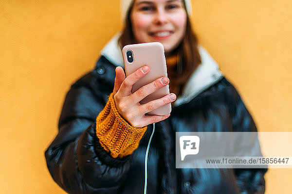 Junge attraktive Frau  die sich mit einem Smartpho fotografiert