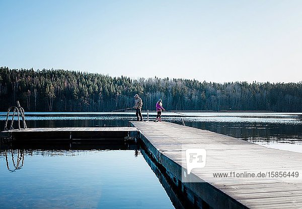 Großvater  der seiner Enkelin das Angeln in einem See in Schweden beibringt