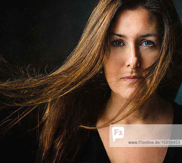 Bildnis einer Frau mit langen braunen Haaren  die über ihr Gesicht wehen.