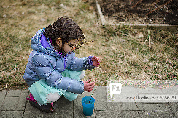 Ein kleines Kind legt zärtlich einen winzigen Baumsprössling in eine Tasse Wasser