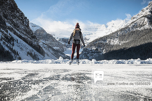Schlittschuhlaufen der Frau auf dem zugefrorenen See am Lake Louse im Banff National Park