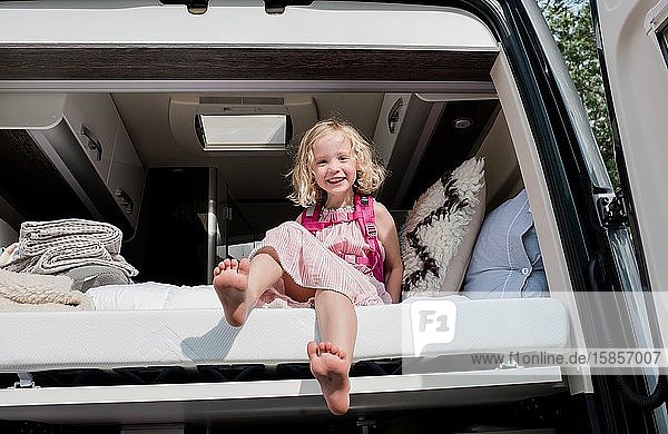 portrait of a young girl sat in bed in a camper van on vacation