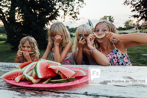 Kleine Kinder haben im Sommer Spaß beim Essen von Wassermelonen im Freien und lachen
