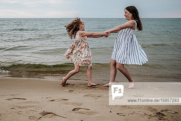 girls spinning and playing on beach along lake michigan