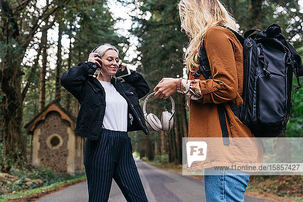 Frauen beim Musikhören mit Kopfhörer auf einem Waldweg auf dem Land