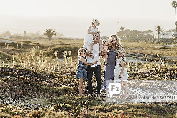 Portrait of family standing in sand at beach during sunset smiling