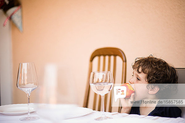 Ein kleiner Junge isst im Sommer draußen einen Pfirsich