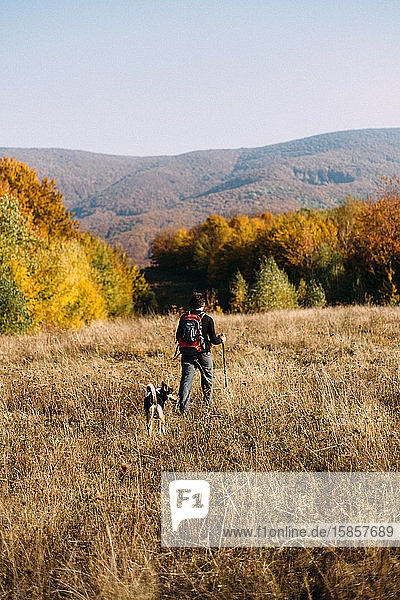 Man and dog hiking in autumn mountains landscape