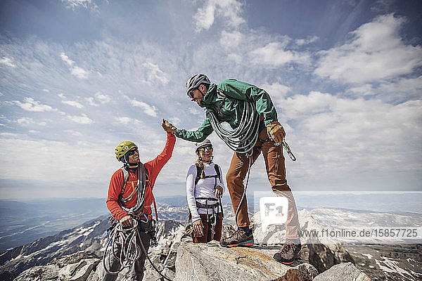 Zwei Männer High Five auf dem Gipfel des Grand Teton  während eine dritte Person zuschaut