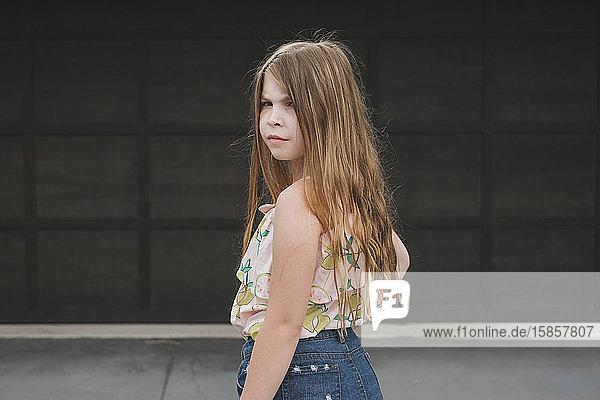 Portrait of a cute young girl standing in front of a garage door