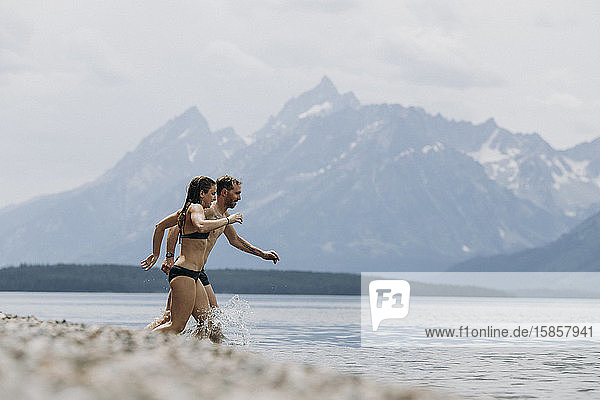 Couple runs into Jackson Lake for a swim  Tetons in the background