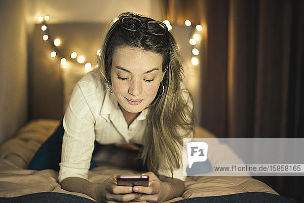 young woman on a bed with a smartphone