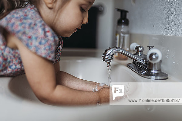 Seitenansicht eines jungen Mädchens  das sich im Waschbecken mit Seife die Hände wäscht