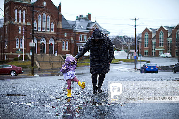 Eine Mutter und ihr Kind spielen an einem regnerischen Tag in Pfützen.