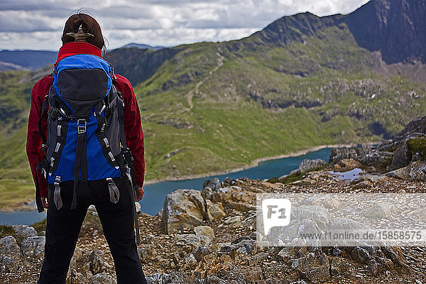 Frau mit Rucksack mit Blick auf einen Bergsee auf Snowdonia