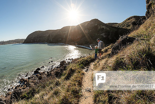 Father and son looking down at ocean from mountain path