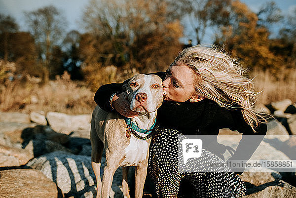 Frau küsst Hund am Strand