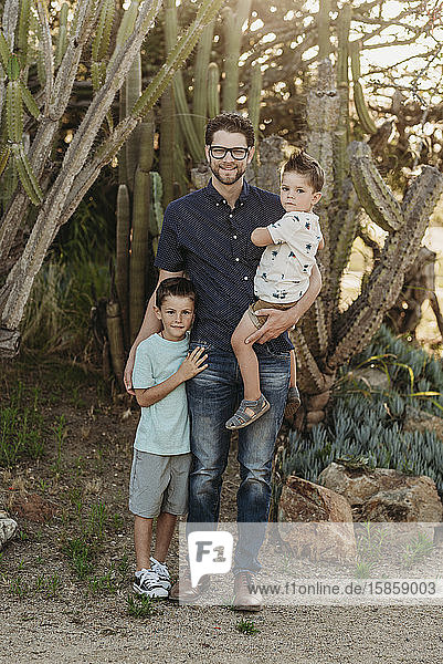 Full length portrait of father and two young boy siblings