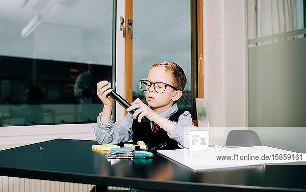 Junge arbeitet in einem Büro  während sein Vater eine Präsentation hält
